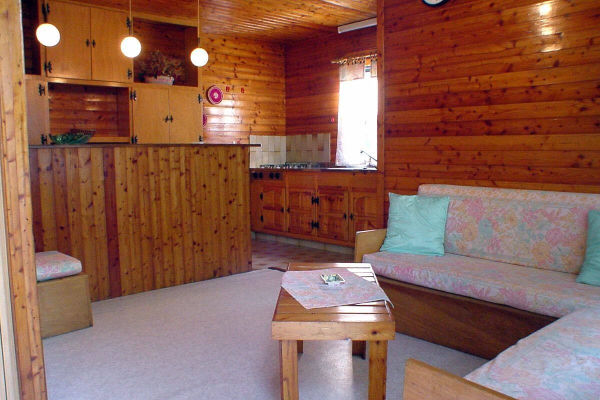 A wooden cabin interior with a kitchenette, a sofa, and a small table.