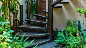 A wooden staircase surrounded by lush greenery, leading to a wooden balcony. - Pousada Mar à Vista (Porto Seguro)