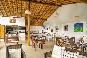A spacious living area with wooden furniture, a dining table, and a kitchen in the background. - Pousada Mar à Vista (Porto Seguro)