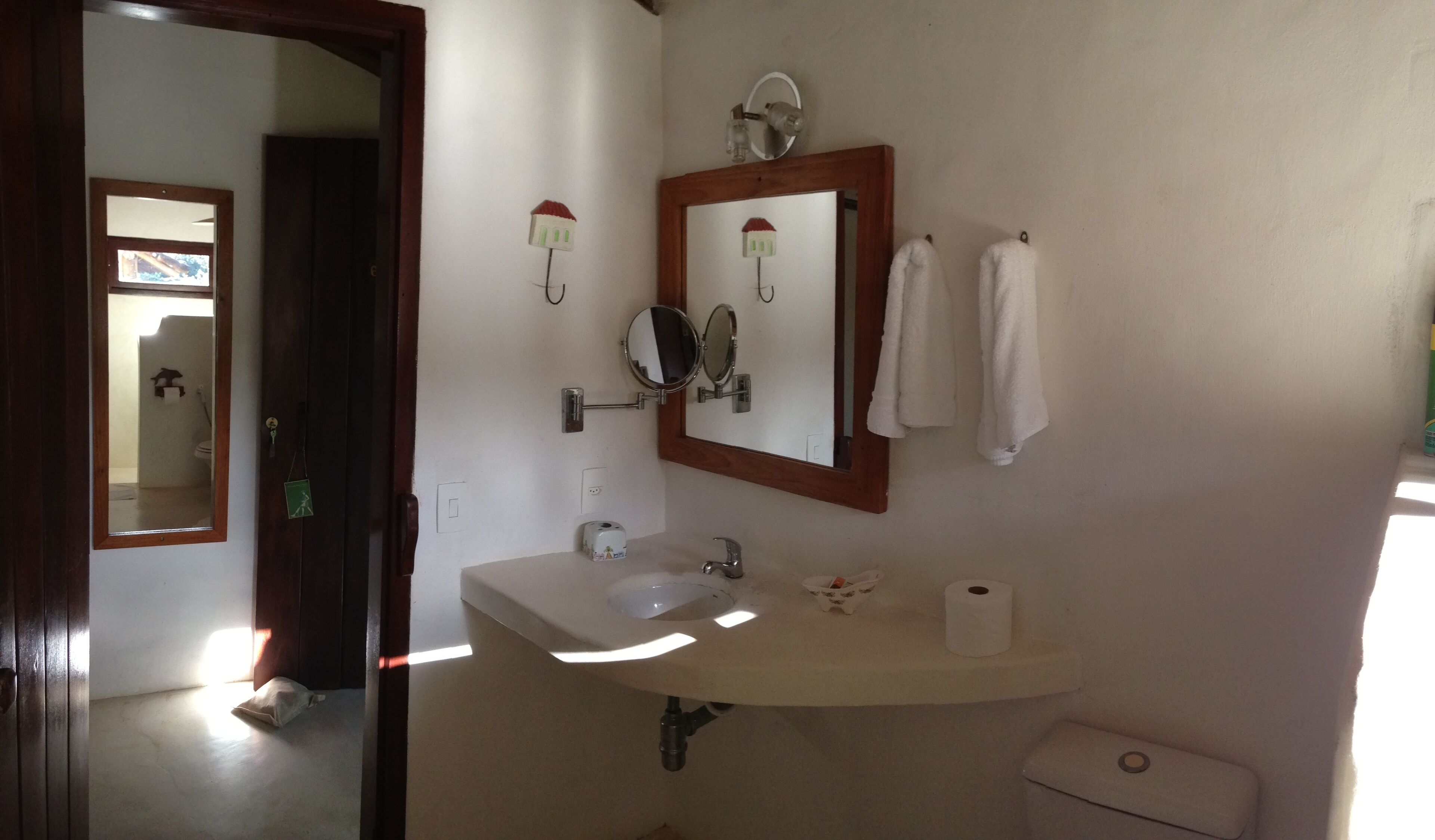 A bathroom with a sink, two mirrors, a toilet, and a towel rack.
