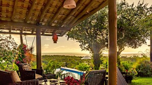 An outdoor dining area with wicker furniture, a pool, and a view of the landscape. - Pousada Mar à Vista (Porto Seguro)