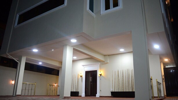 A hotel entrance with a covered walkway, a dark entrance door, and two wall-mounted light fixtures. - Rightgate Hotel & Suites (Lagos)