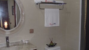 A bathroom with a toilet, a sink with a mirror, and a towel rack with a towel. - Rightgate Hotel & Suites (Lagos)