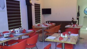 A dining area with red chairs, tables set with white plates, glasses, and cutlery. - Rightgate Hotel & Suites (Lagos)