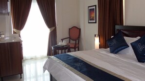 Quarto de hotel com uma cama grande, uma escrivaninha com cadeira e um quadro na parede.