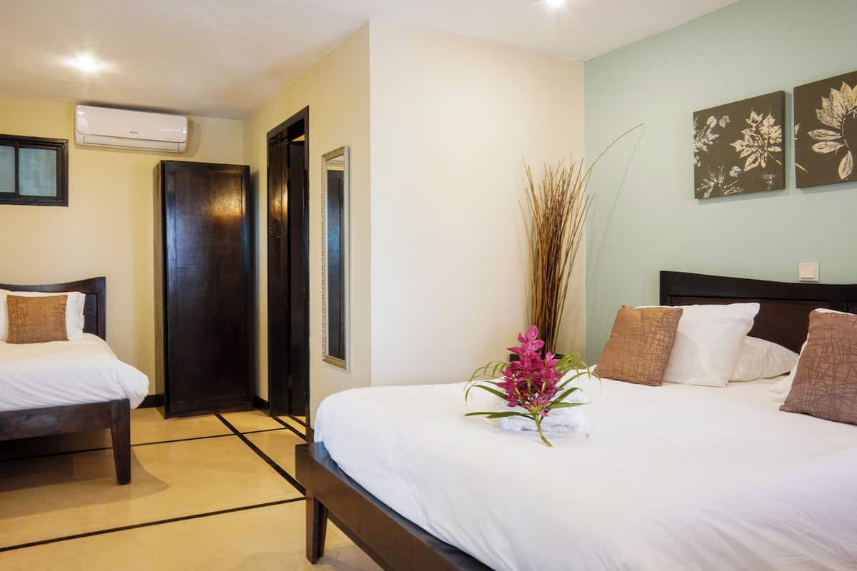 A hotel room with a large bed, a smaller bed, a desk, and a wardrobe.