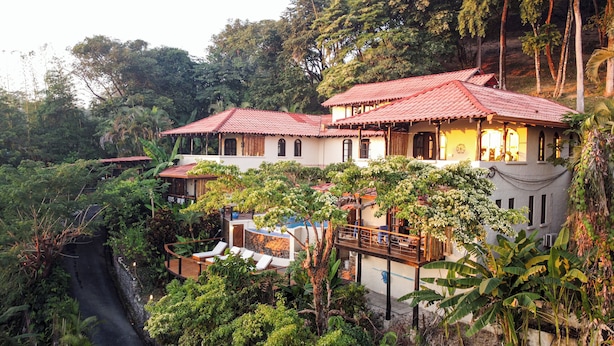 A multi-story house with red-tiled roofs, surrounded by lush greenery and trees. - Casa Marbella (Cóbano)