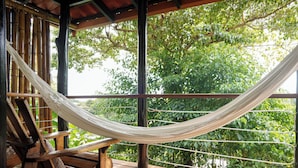 A hammock between wooden chairs on a wooden deck with a view of lush green trees. - Casa Marbella (Cóbano)