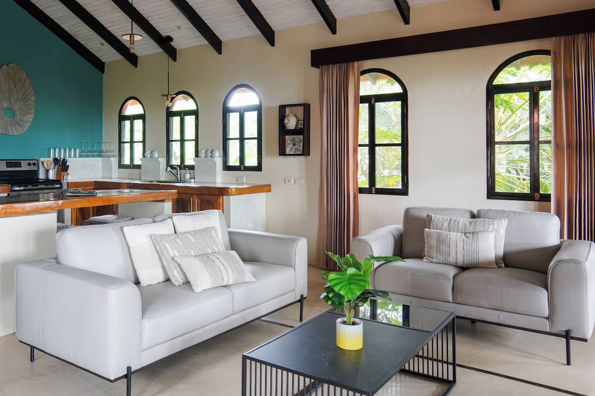 A modern living room with two sofas, a coffee table, and a kitchen area with a counter and cabinets.
