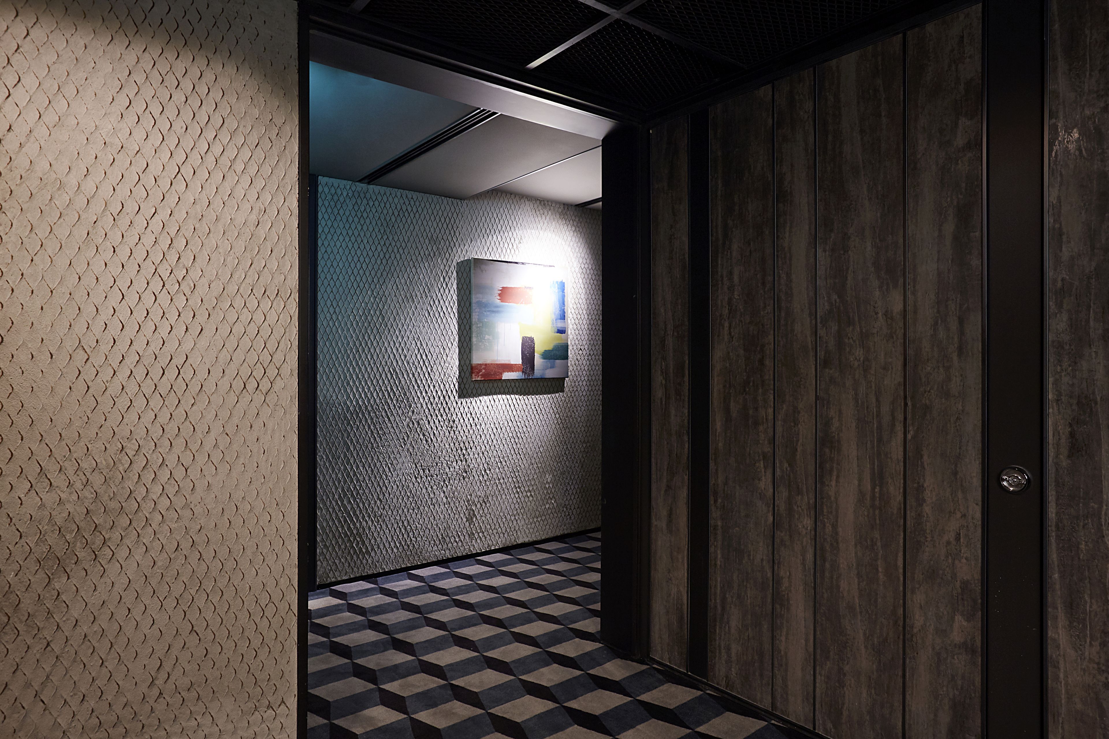 A hallway with a patterned floor, a textured wall, and a framed artwork.