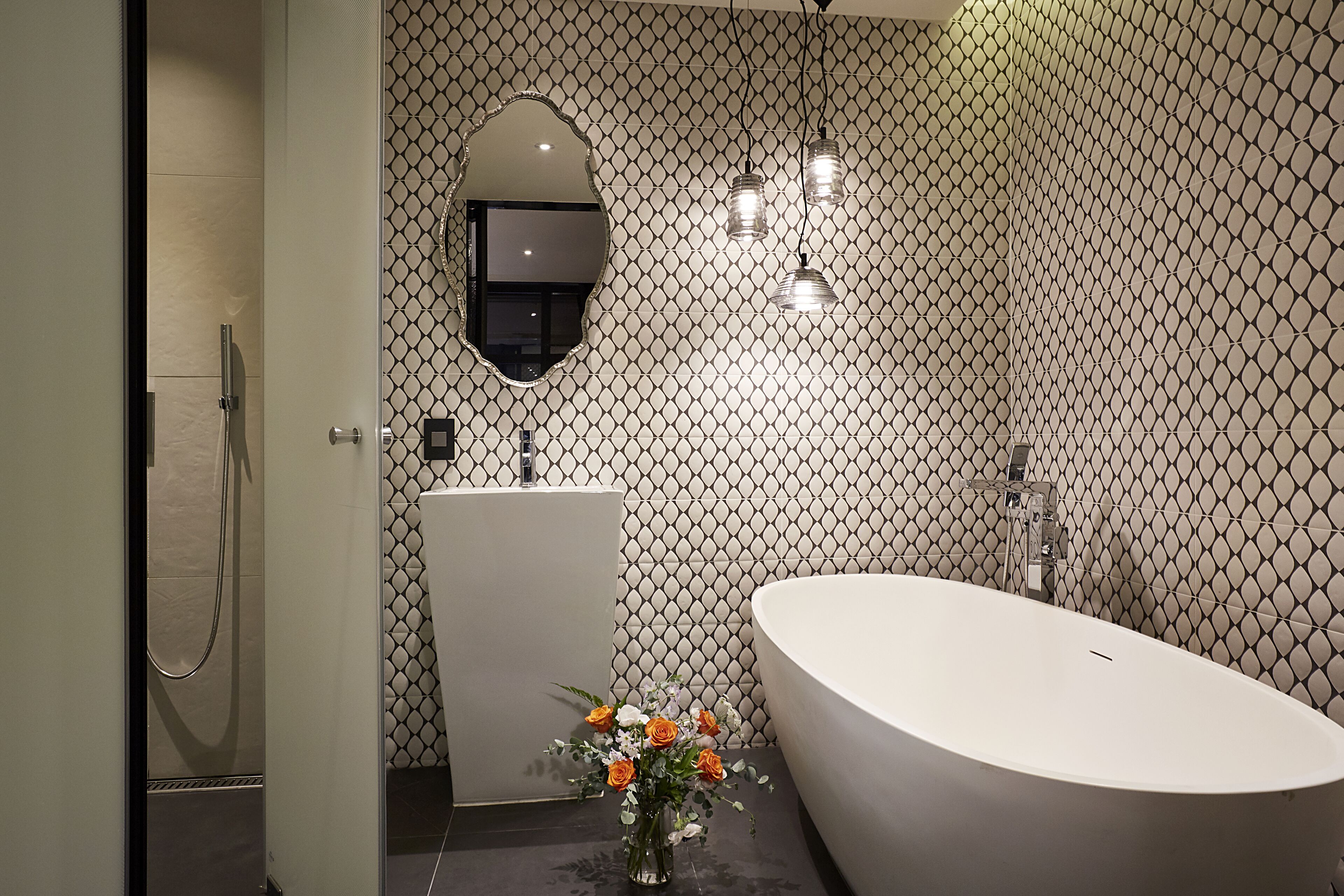 A modern bathroom with a freestanding bathtub, a vanity with a mirror, and a shower area.