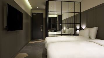 A modern hotel room with a large bed, a TV mounted on the wall, and a mirror reflecting the room.