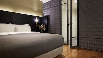 Un dormitorio moderno con una cama grande, una mesita de noche con un florero y un armario con estampado geométrico.