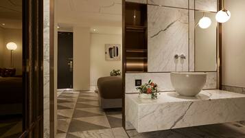 Un baño moderno con tocador de mármol, un espejo grande y un piso con diseño geométrico.