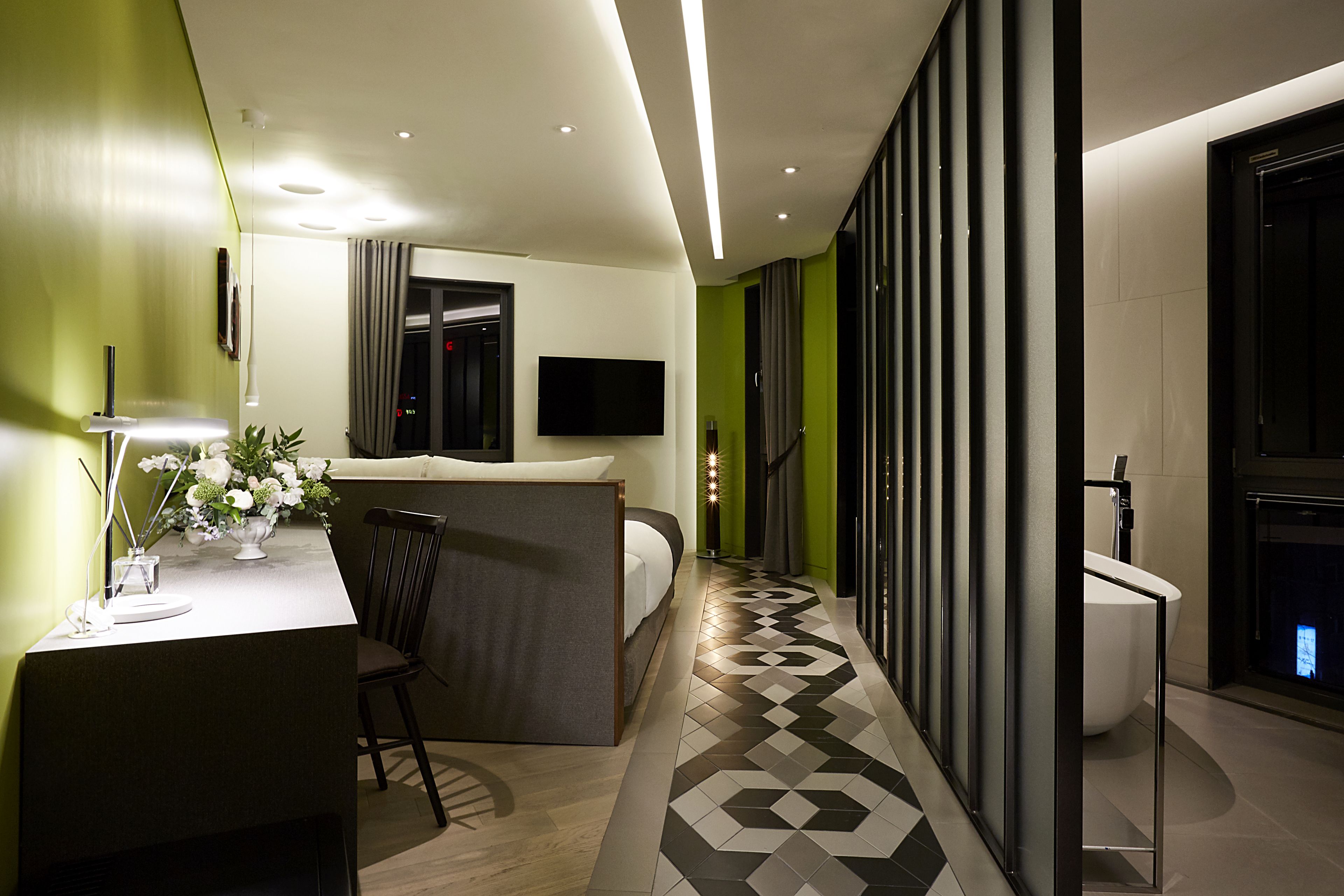 A modern hotel room with a bed, desk, and a TV.