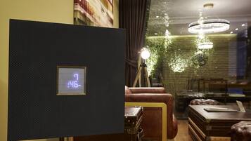 Una habitación con un reloj digital, un sofá de cuero, una mesa de madera y vistas a zonas verdes.