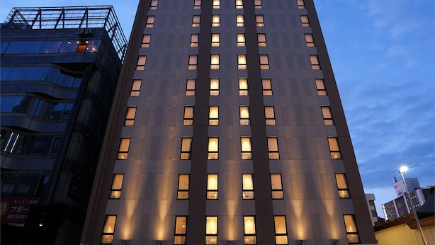 Un hôtel moderne à la façade plate, doté de plusieurs étages et de fenêtres régulièrement espacées.
