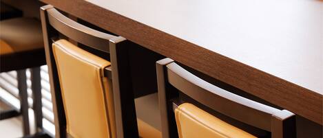 Una larga mesa de madera con dos sillas, cada una con asiento de cuero.