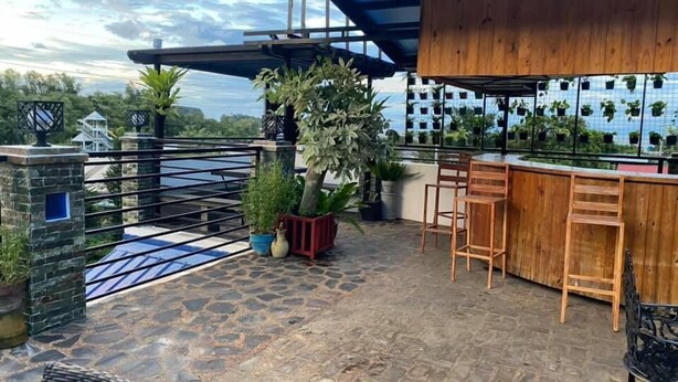 A rooftop bar with stone flooring, wooden bar stools, and potted plants. - Makiling Onsen Hotel (Los Banos)
