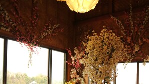A wooden interior with a table and benches, large windows, and hanging paper lanterns. - Makiling Onsen Hotel (Los Banos)