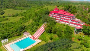 A large hotel with a red roof, a swimming pool, and a red and white building. - Caliraya Resort Club (Lumban)