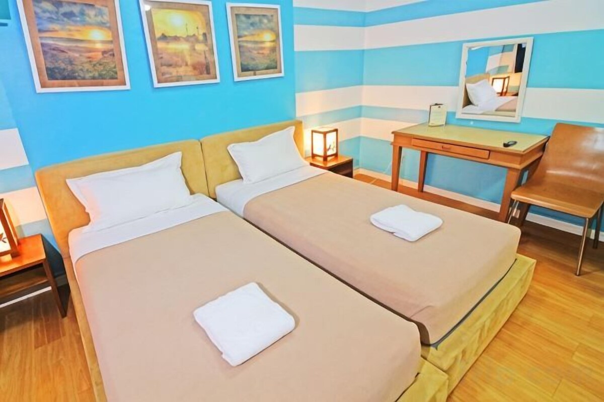 A hotel room with two beds, a desk, a chair, and a nightstand.