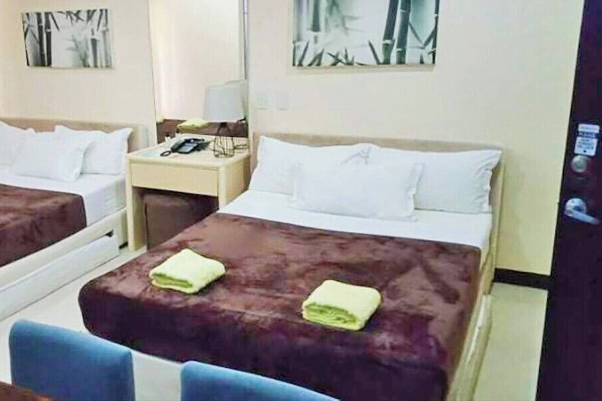 A hotel room with two beds, a desk, a chair, and artwork on the walls.