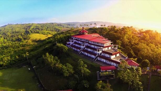 A large, multi-story building with a red roof, surrounded by lush greenery and hills. - Caliraya Resort Club (Lumban)