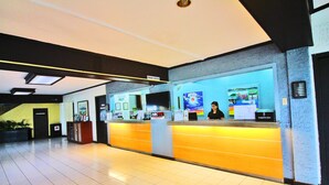 A hotel reception area with a reception desk, a digital screen, and a sign indicating the front office. - Caliraya Resort Club (Lumban)