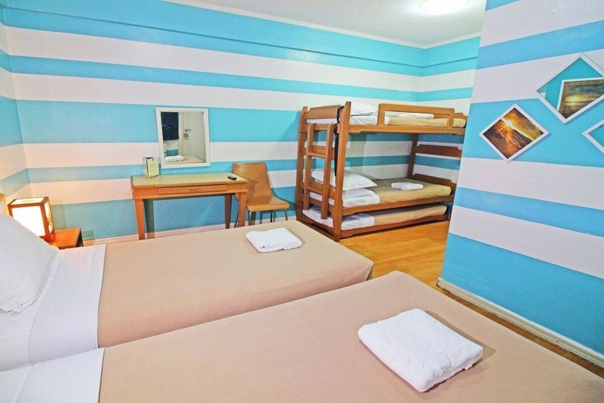 A room with striped walls, bunk beds, a desk, and a chair.