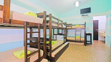 A room with bunk beds, a television, and a door.