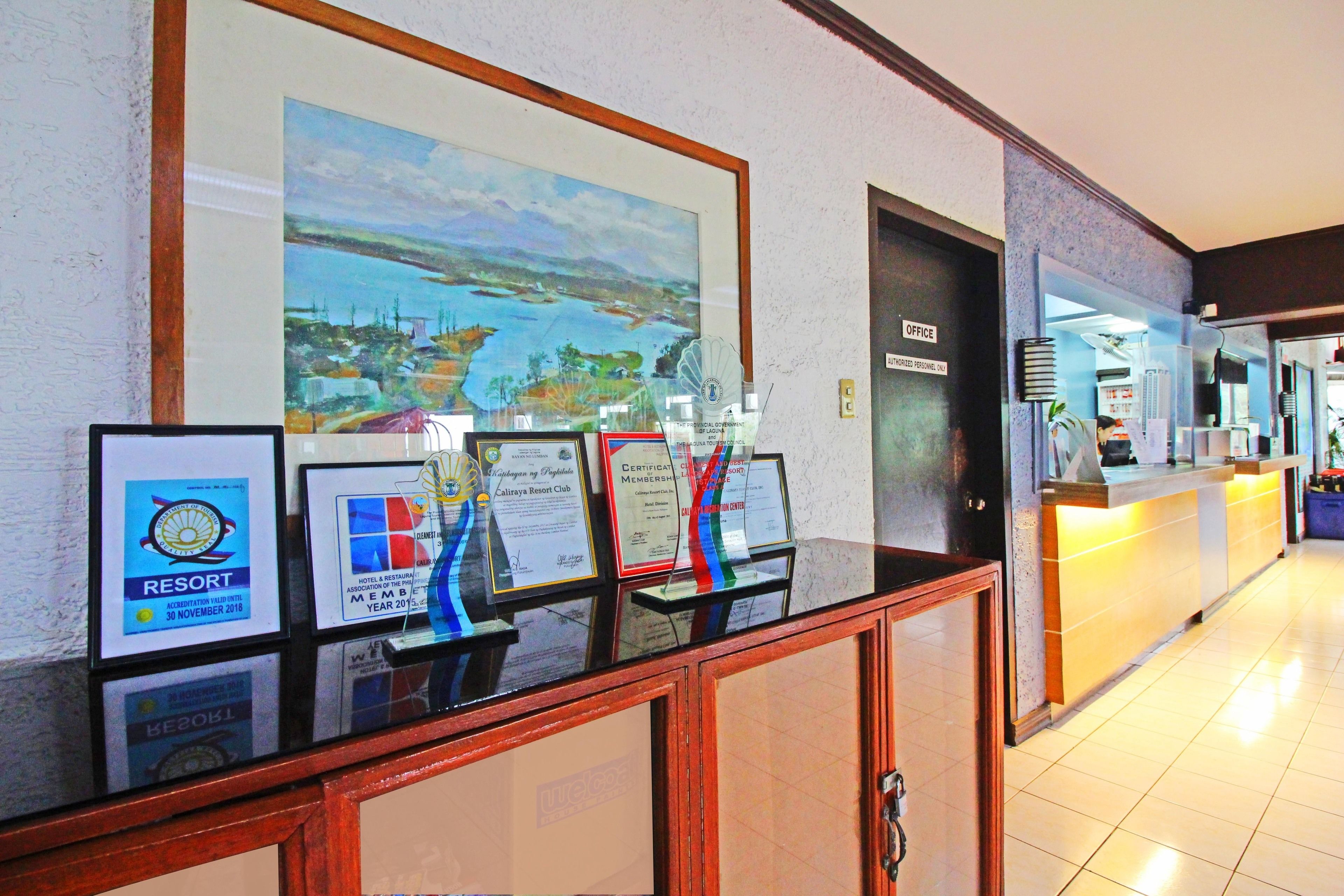 A reception area with framed awards, a large landscape painting, and a reception desk.