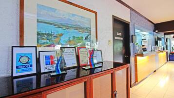 A reception area with framed awards, a large landscape painting, and a reception desk.