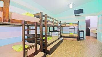 A dormitory room with bunk beds, a television, and a door.
