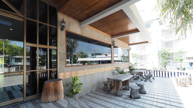 An outdoor seating area with tables and chairs, a wooden ceiling, and a tiled floor. - Pachara Hotel and Restaurant (Suphan Buri)