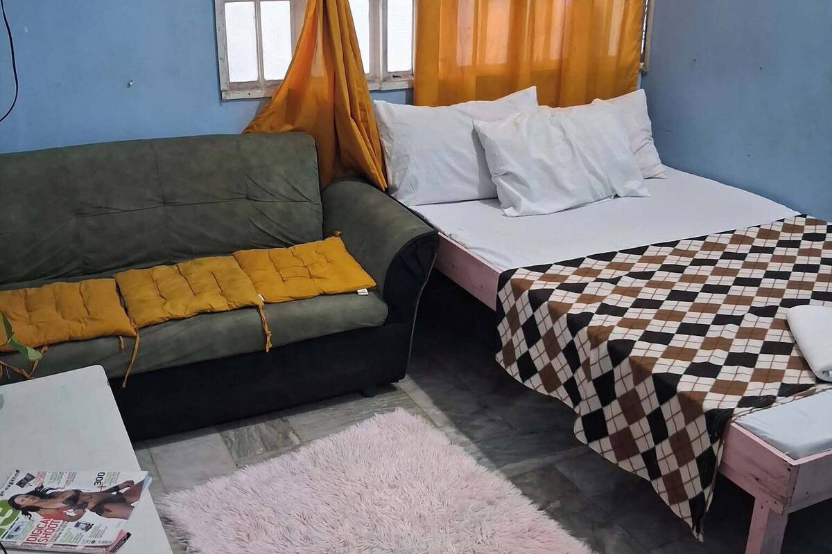 A room with a bed, a sofa, a small table, and a window with curtains.