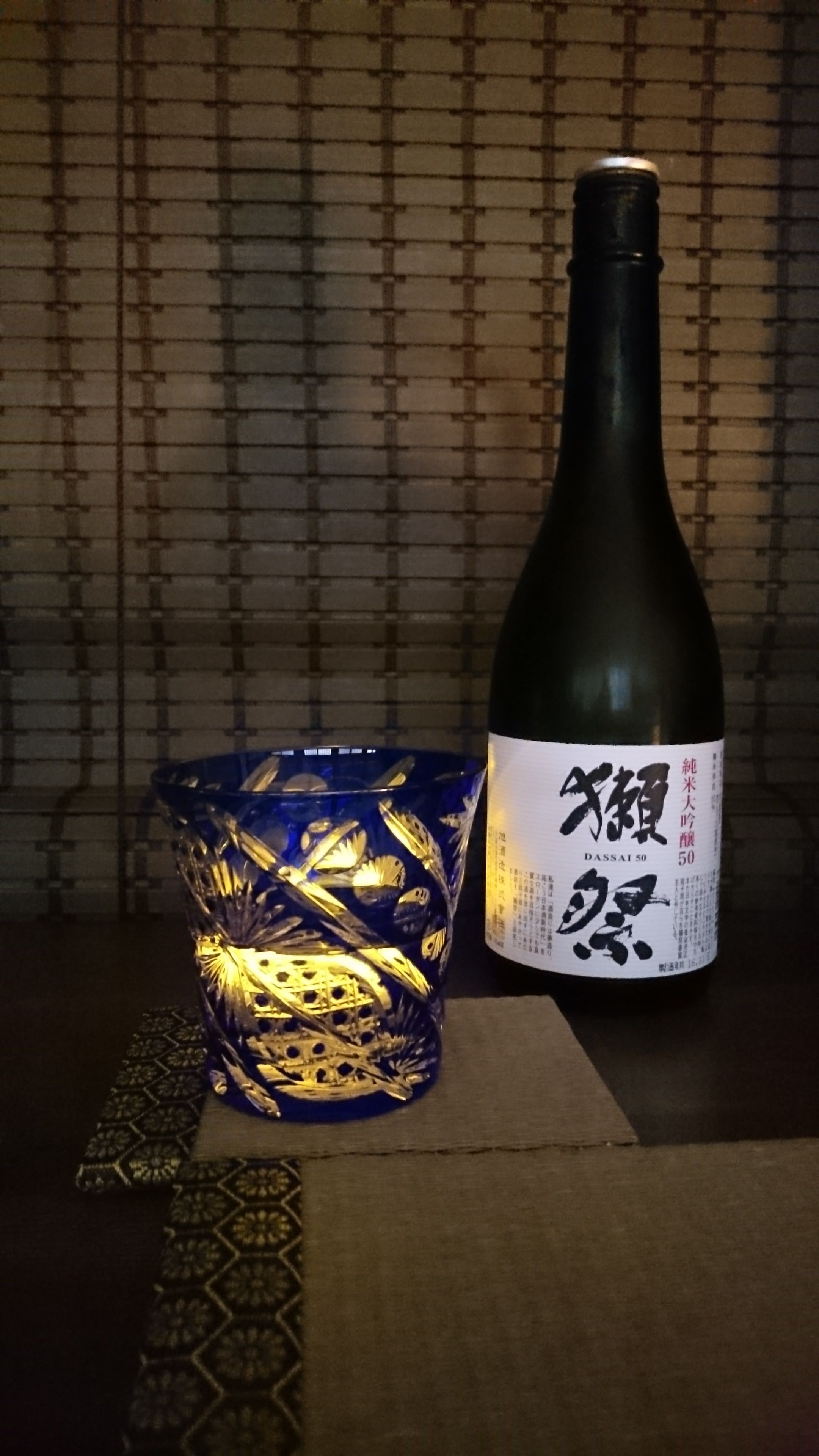 A bottle of sake with a label and a decorative glass.