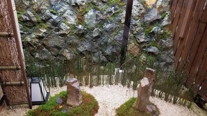 A garden with a rock wall, two rock sculptures, a wooden deck, and a solar-powered lamp. - Kyonoyado Senkakubettei (Kyoto)