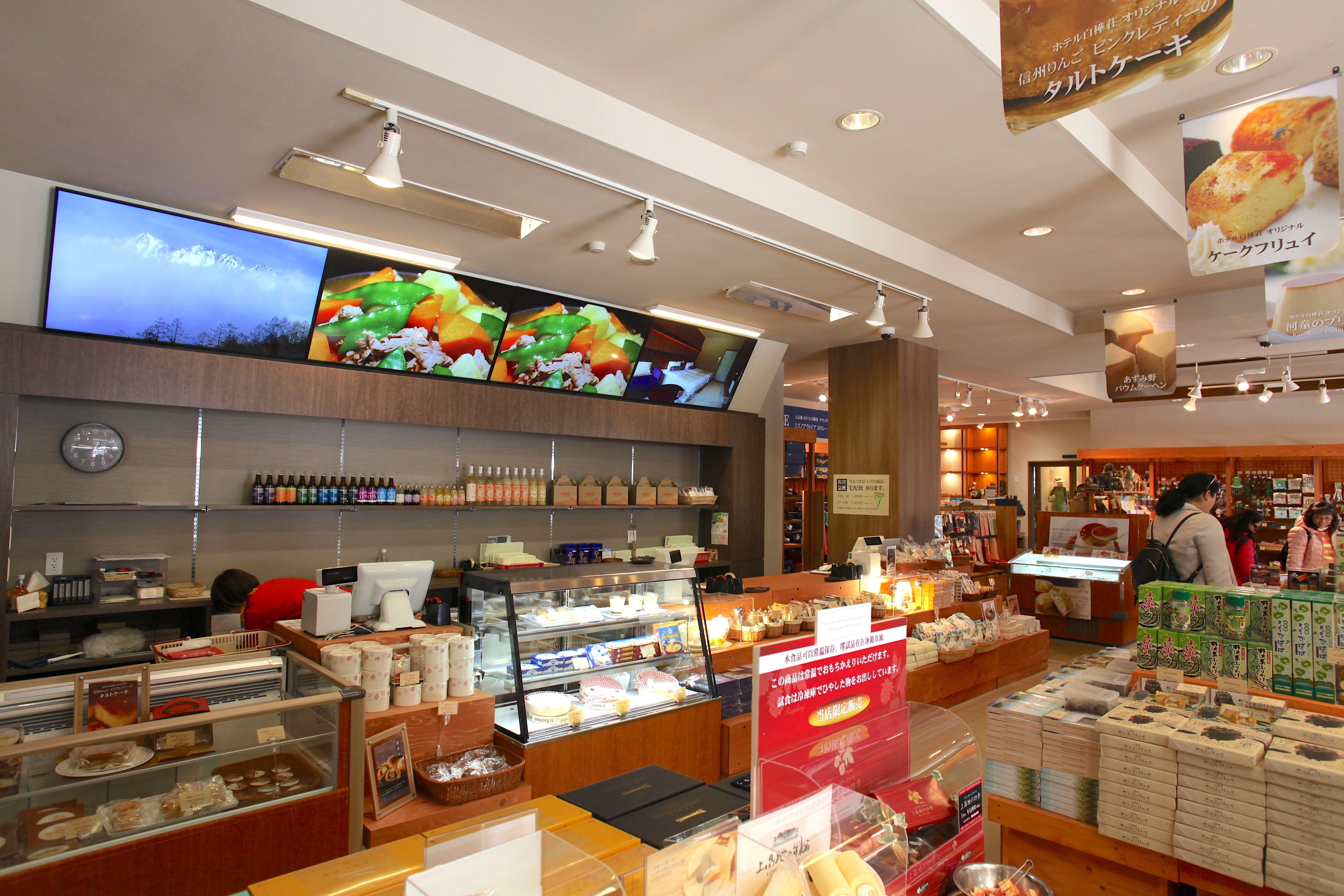A bakery with a display case of pastries, a digital menu board, and shelves of packaged goods.