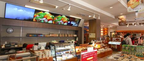 A bakery with a display case of pastries, a digital menu board, and shelves of packaged goods.