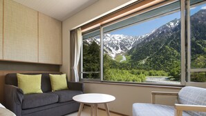 A modern room with a sofa, a small round table, and a view of a mountainous landscape through a large window.