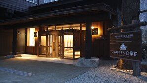 A hotel entrance with a wooden facade, glass doors, and a signboard.