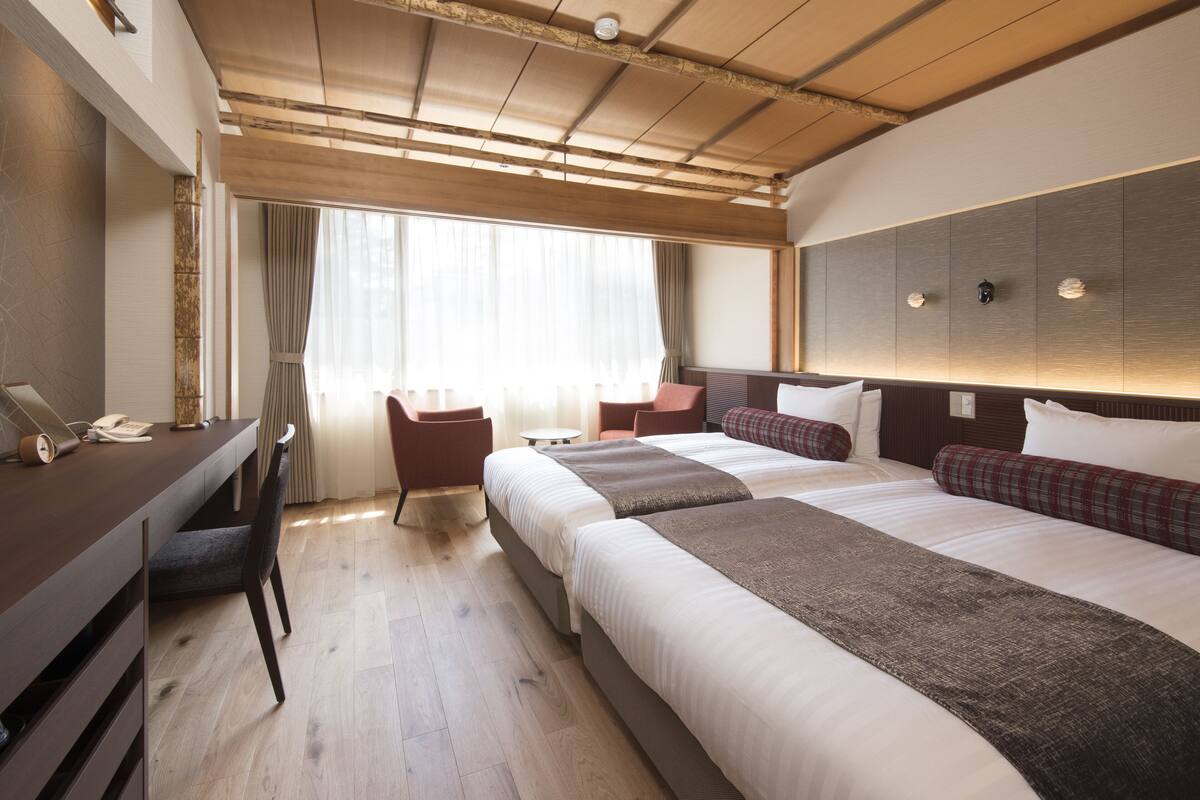 A hotel room with a large bed, a desk, and a chair.