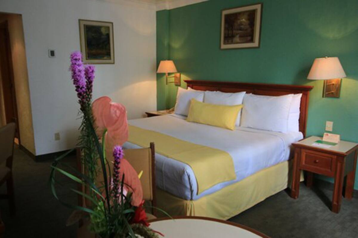 A hotel room with a bed, two bedside tables, a chair, and a desk.