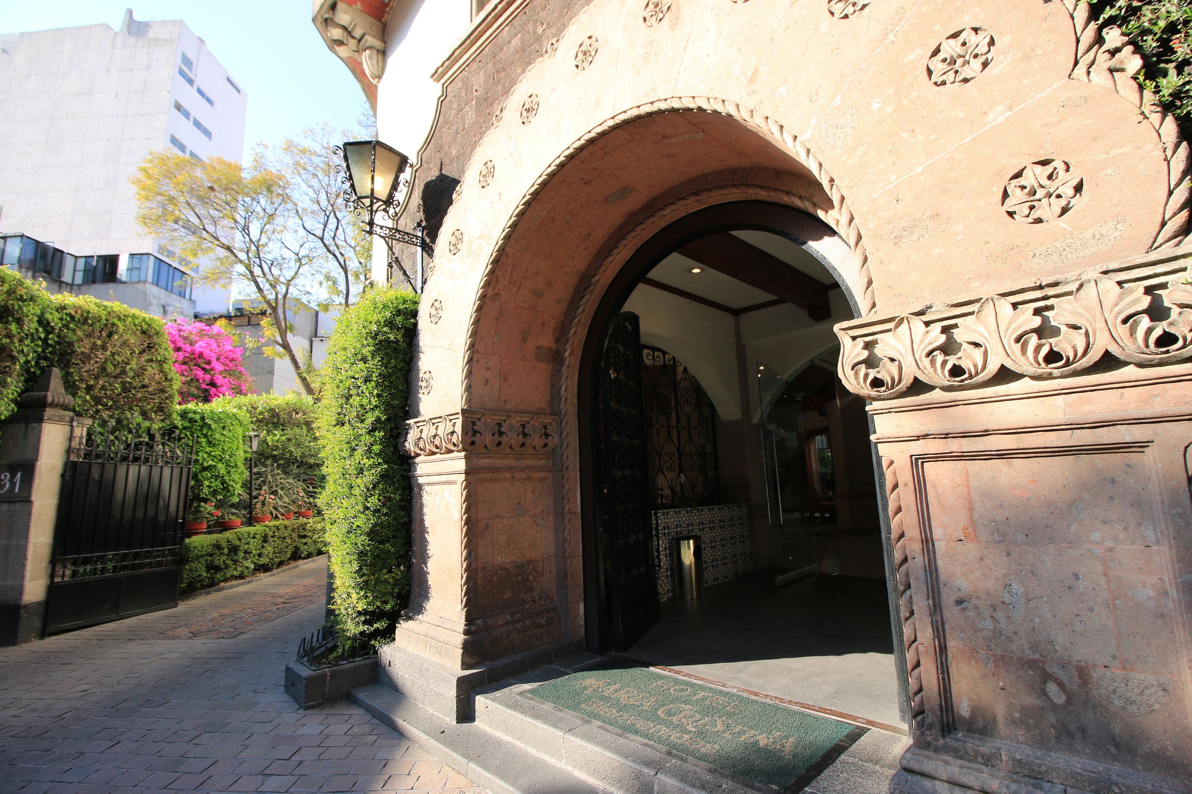 Una entrada con un arco, felpudo y un camino pavimentado que lleva a un edificio.