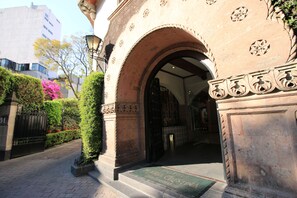 An entrance with an arched doorway, a doormat, and a paved pathway leading to a building.