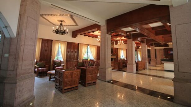 A spacious lobby with wooden furniture, chandeliers, and a high ceiling.