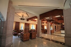 Un vestíbulo amplio con mobiliario de madera, candelabros y un techo alto.