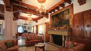 A spacious living room with wooden furniture, a fireplace, and a large painting on the wall.