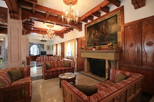 Un salón amplio con muebles de madera, una chimenea y un cuadro grande en la pared.